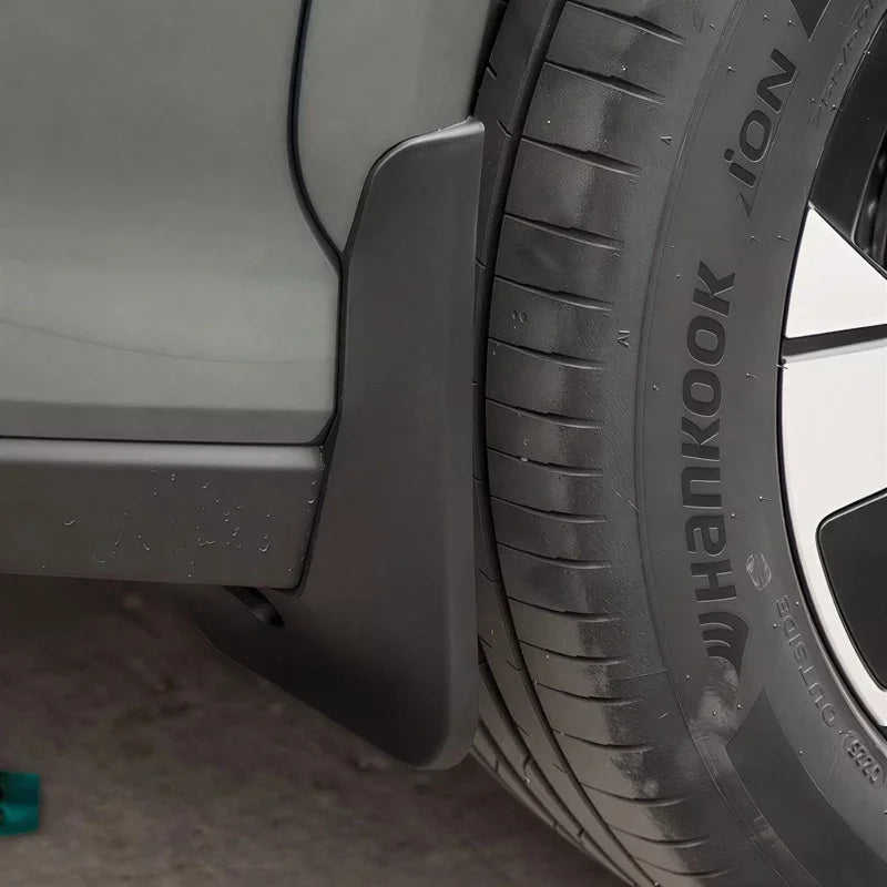 Close-up of a matte black durable plastic mud guard installed behind a car tire.