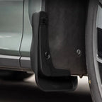 Close-up of a durable black matte plastic mud flap installed on a vehicle wheel arch.