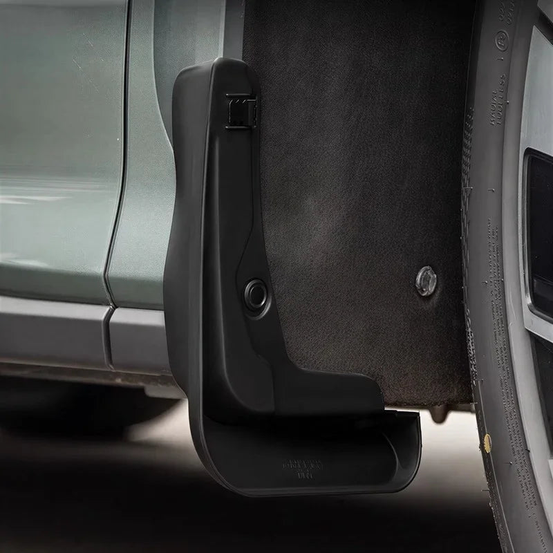Close-up of a durable black matte plastic mud flap installed on a vehicle wheel arch.