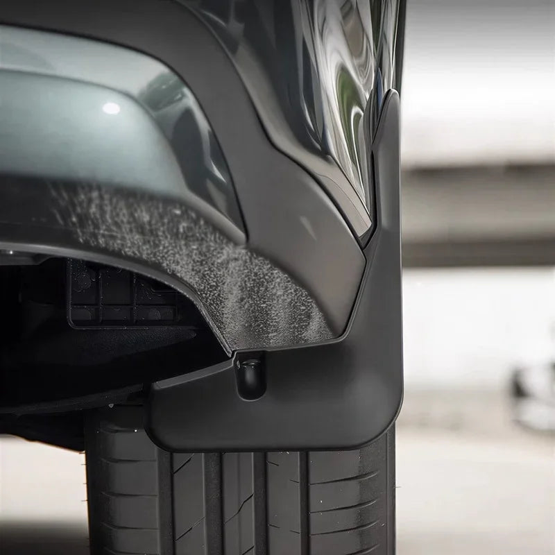 Close-up of a durable matte black plastic mudguard installed on a grey vehicle.