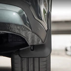 Close-up of a durable matte black plastic mudguard installed on a grey vehicle.