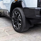 Black durable rubber mud flap installed on a white vehicle wheel arch for protection.