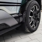 Black durable plastic mud flap installed on a silver car wheel arch for splash protection.