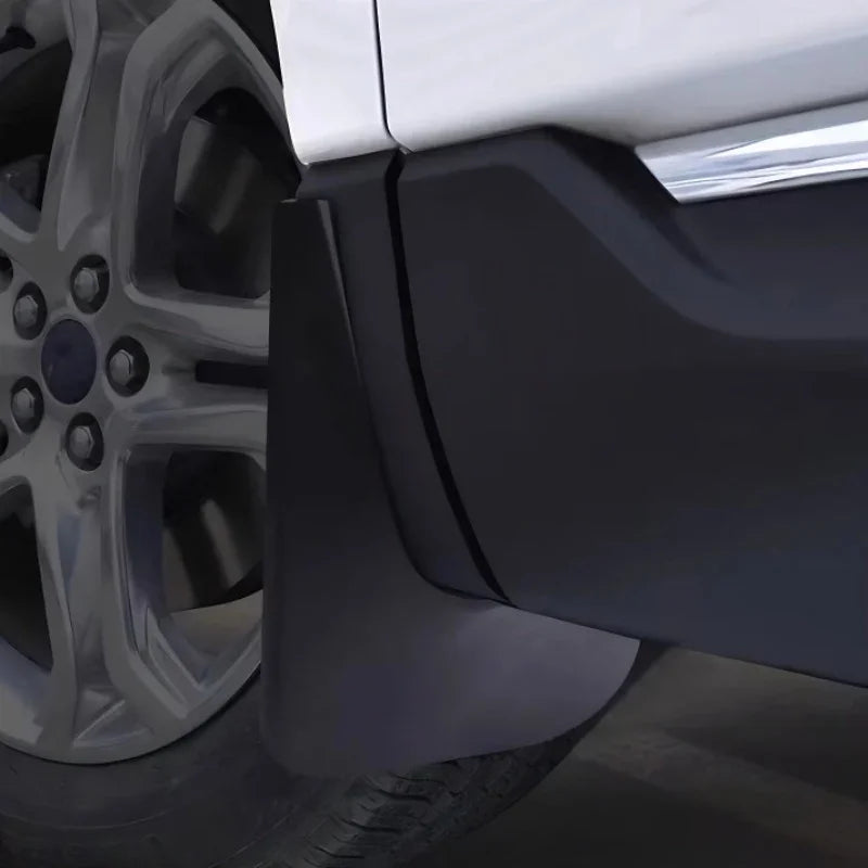 Black matte durable rubber mud flap installed on a white vehicle wheel arch for protection.