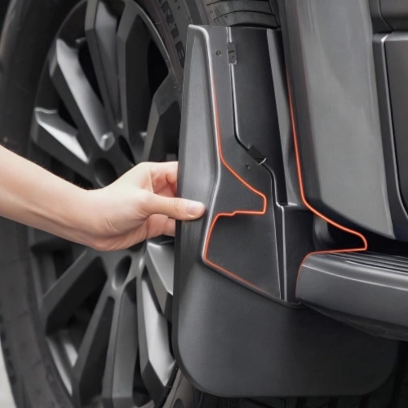 Hand touching a matte black durable plastic car mud guard with red outline detailing.