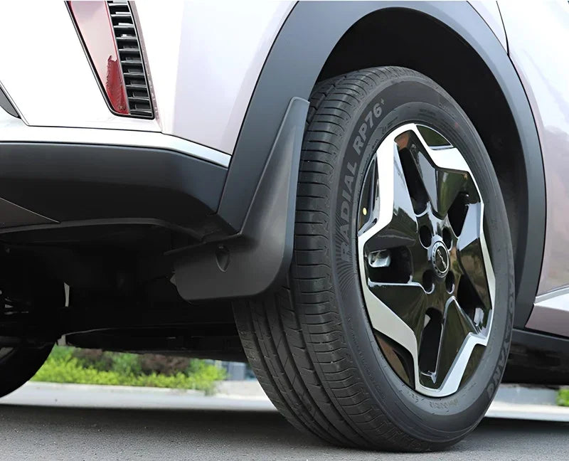 Black matte durable rubber mud flap installed behind the tire of a white SUV.