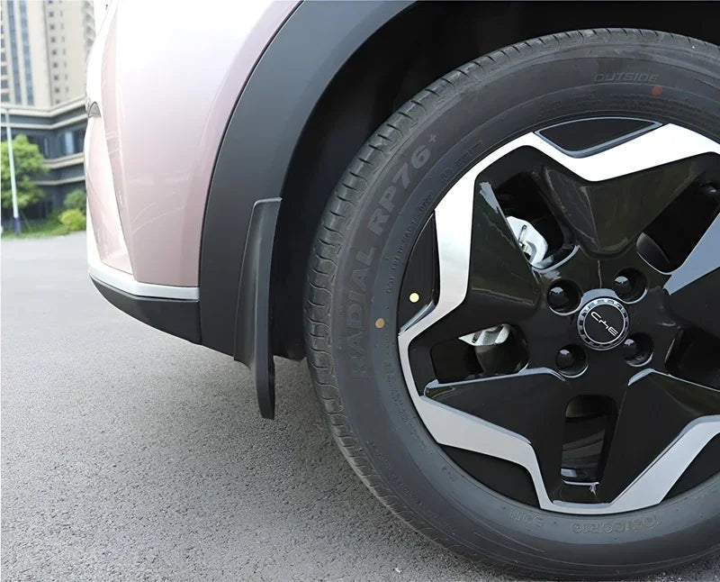 Black protective mud flap installed behind the wheel of a pink BYD car.