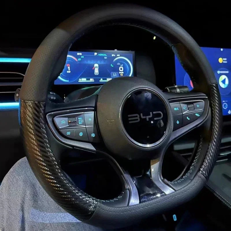Interior view of a BYD steering wheel featuring a black leather and carbon fiber texture grip.