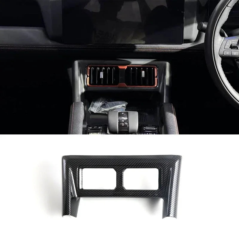 Black carbon fiber trim panel for car center console air vent surround.