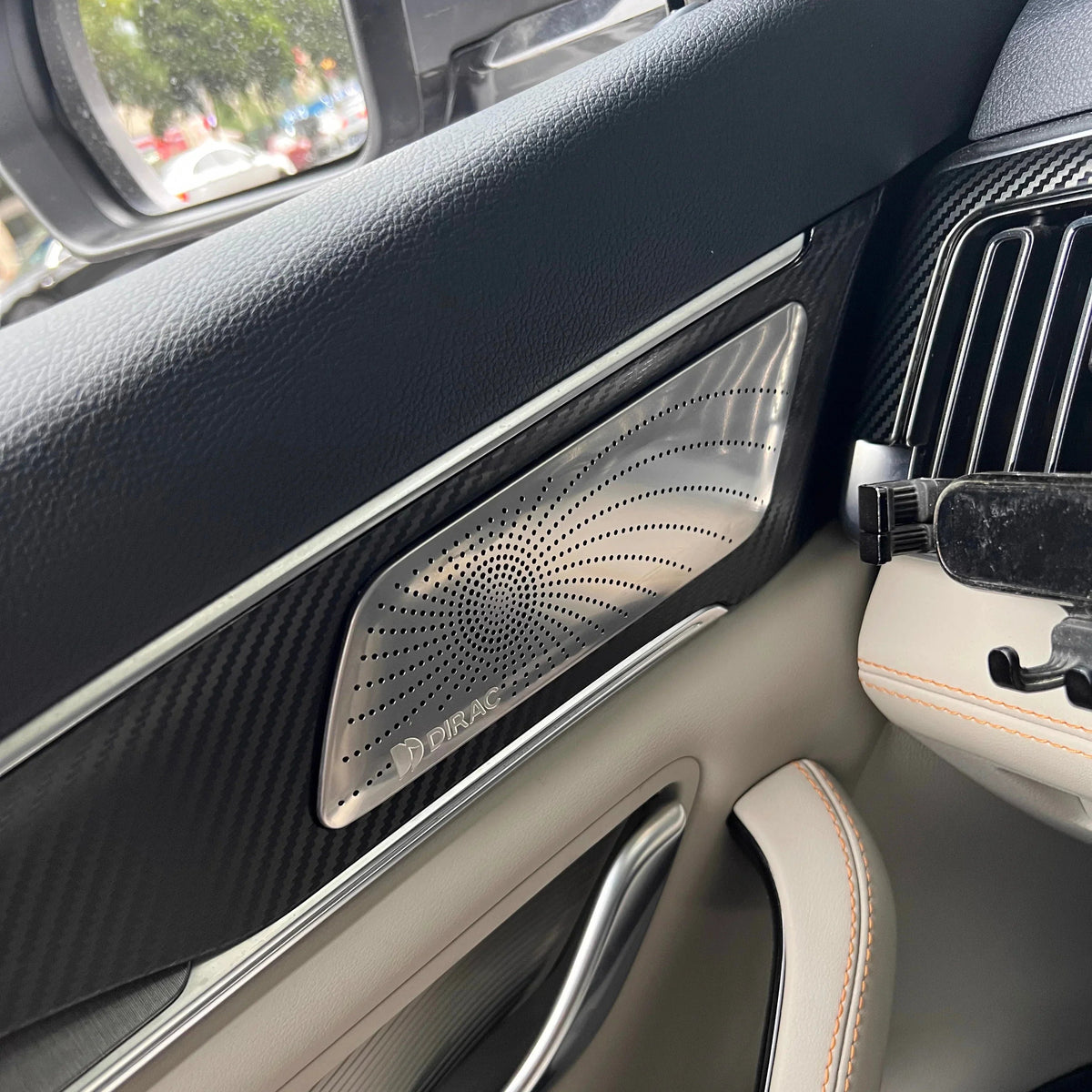 Black carbon fiber texture car door panel with a silver Dirac premium speaker grille.