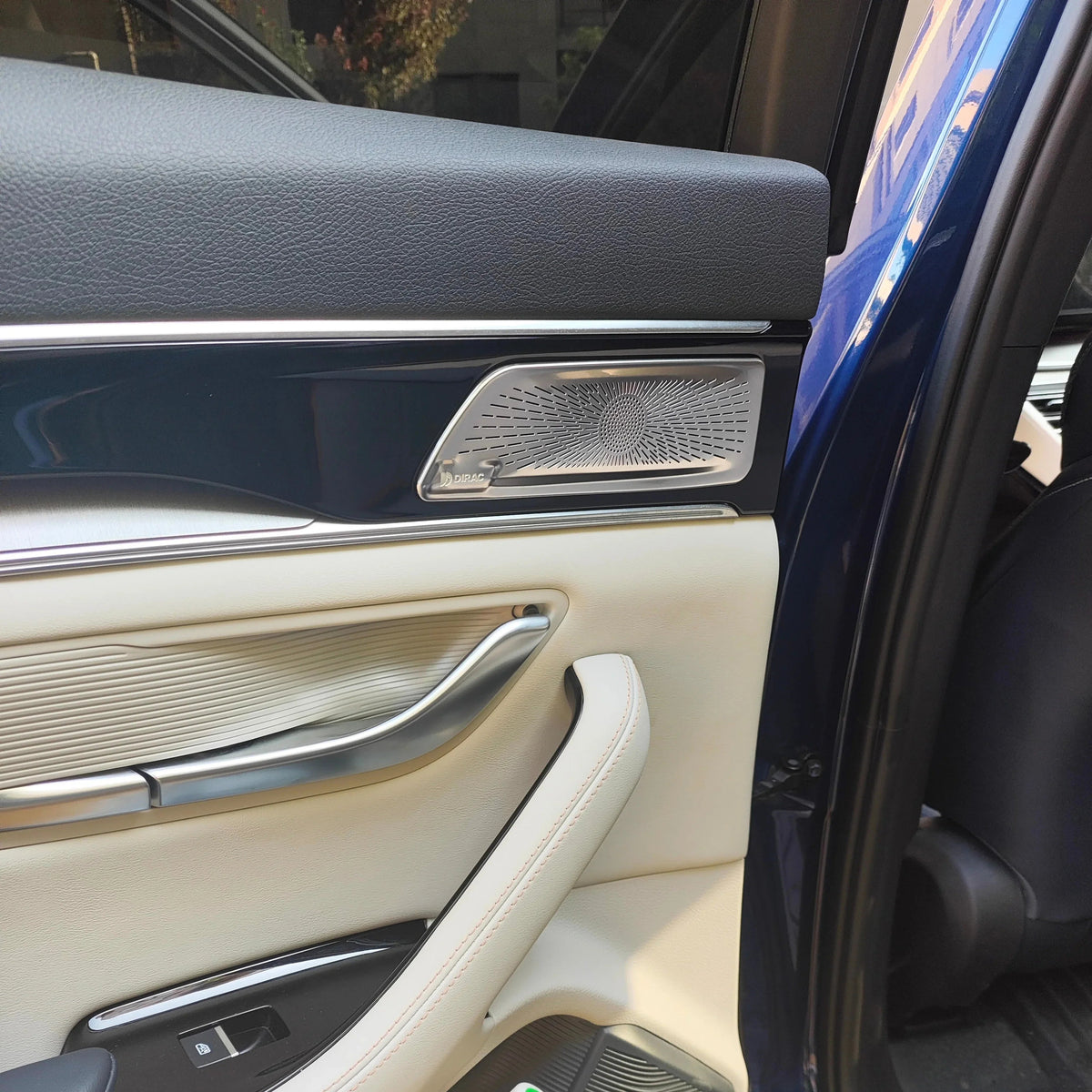Premium cream leather car door panel with black trim and silver metallic speaker grille.