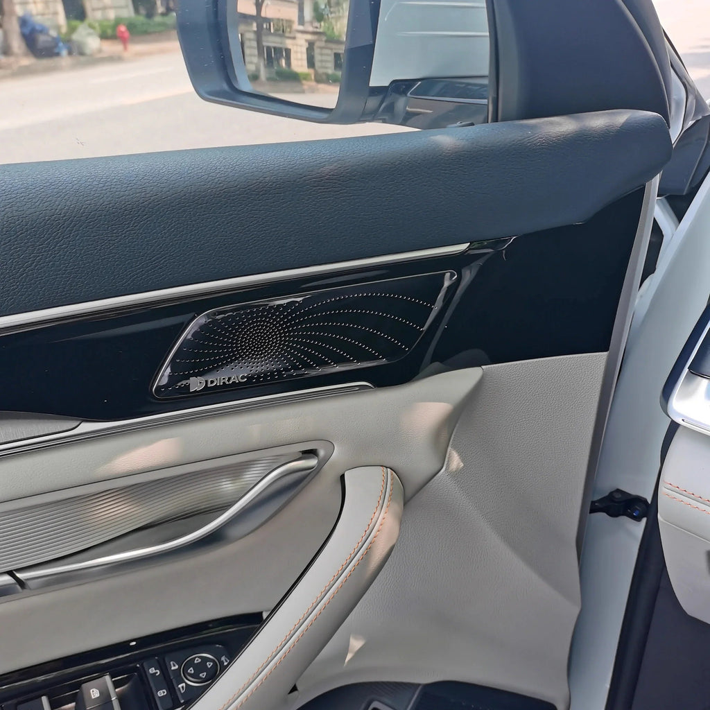 Black Dirac premium speaker grille integrated into a grey leather car door panel.