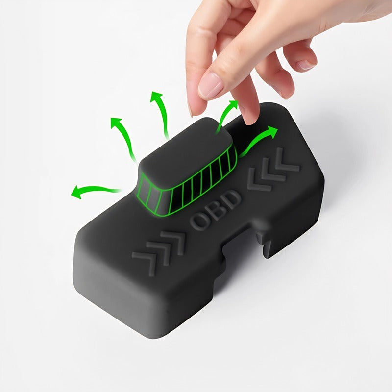 Hand touching a black matte silicone OBD port cover with green airflow indicators.