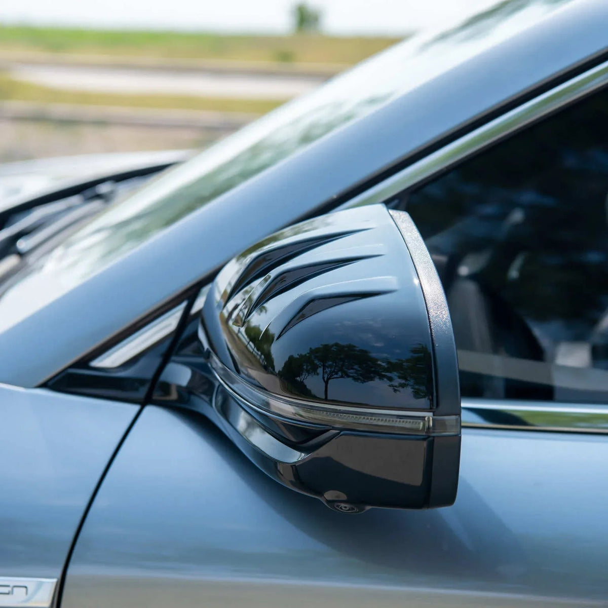 Glossy black aerodynamic side mirror cover for BYD, featuring a sleek textured design.