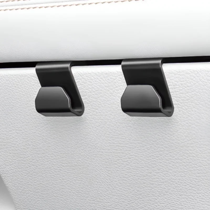 Two matte black heavy-duty car seat headrest hooks mounted on white leather upholstery.