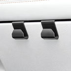 Two matte black heavy-duty car seat headrest hooks mounted on white leather upholstery.