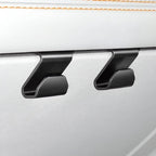 Two matte black durable plastic seat back hooks mounted on a white leather car interior.