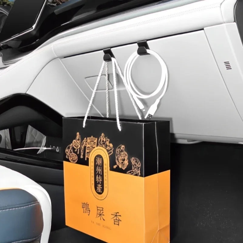 Black and orange paper shopping bag hanging from a white car interior storage hook.
