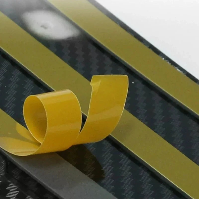 Flexible gold-colored adhesive tape strip with a carbon fiber texture pattern.