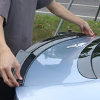 A person installing a sleek black carbon fiber rear spoiler on a light blue BYD car.