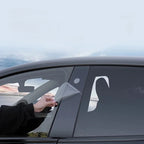 Hand applying a transparent protective film to a black car window for scratch resistance.