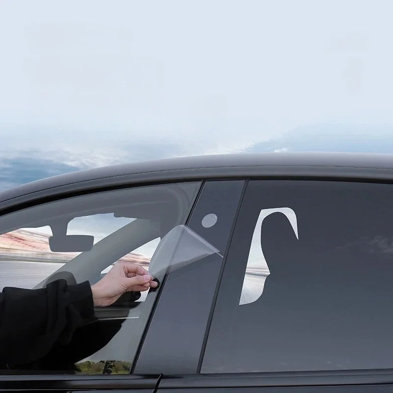 Hand applying a transparent protective film to a black car window for scratch resistance.