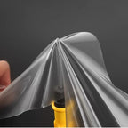 Transparent protective film being applied to a yellow component, featuring a smooth and clear finish.
