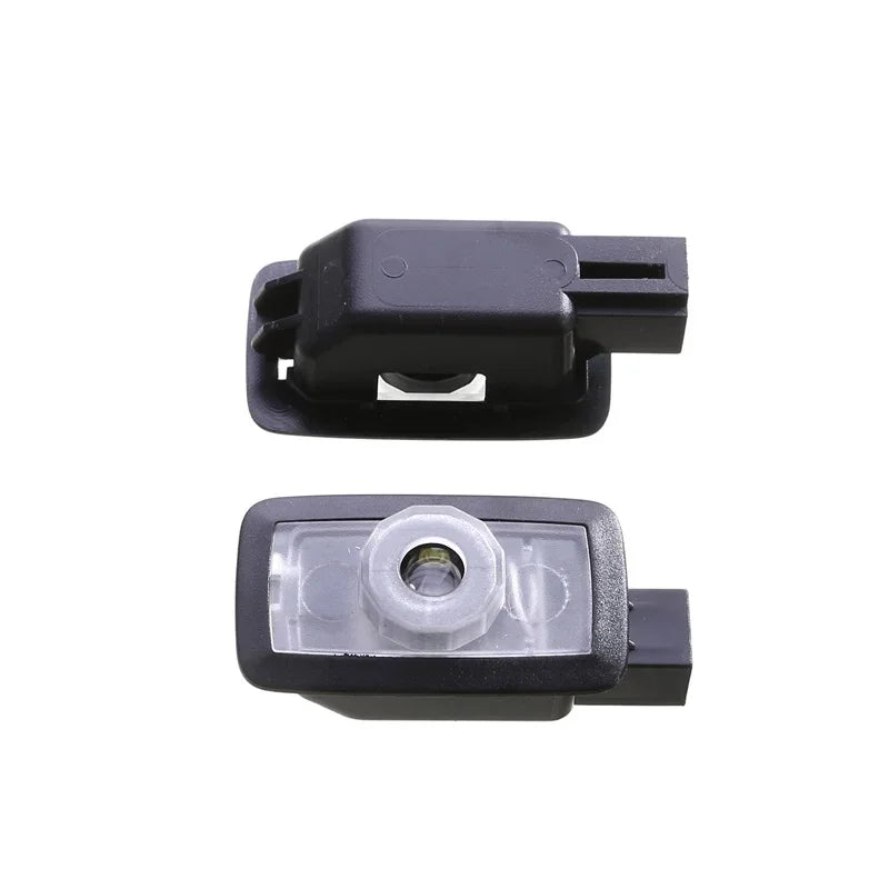 Two black plastic automotive light switch components featuring a clear lens and durable housing.