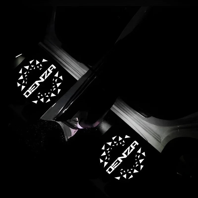 Illuminated white DENZA door sill protector plates with geometric patterns in dark interior.