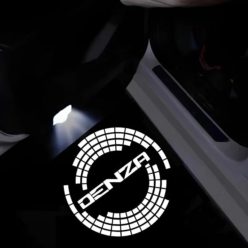 White LED puddle light projecting the DENZA logo onto a dark car door sill.