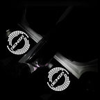 Glowing white DENZA logo welcome light projections on a dark car floor mat.