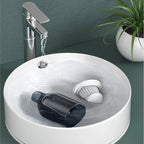 White ceramic vessel sink with a chrome faucet and a black bottle floating in water.