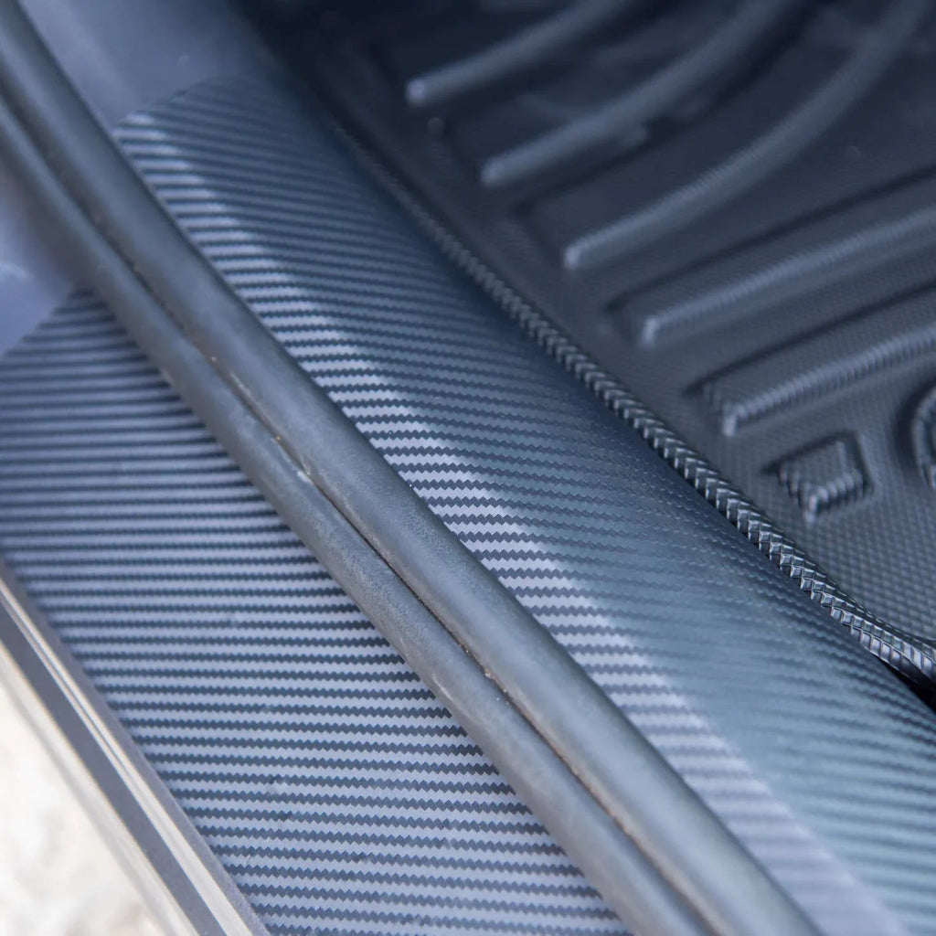 Close-up of a black carbon fiber texture car interior trim protector.