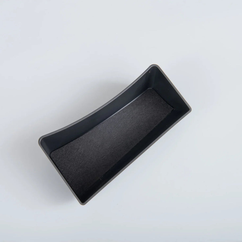 Curved black matte storage tray with a non-slip felt lining for car interior organization.