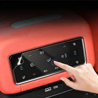 A hand interacting with a black digital touchscreen control panel on a red leather car interior surface.