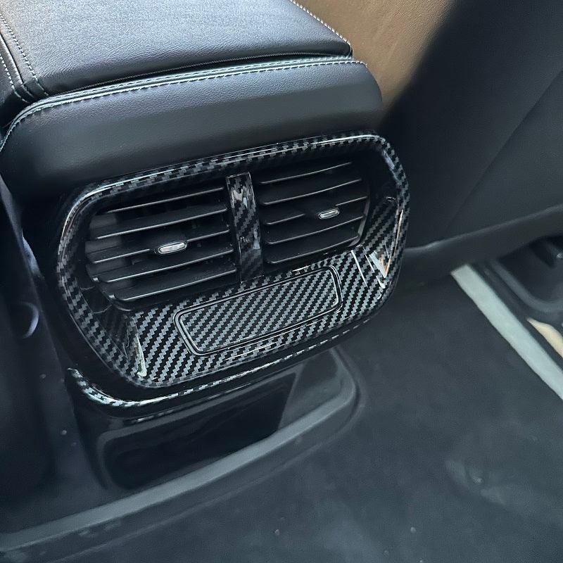 Carbon fiber pattern rear air vent trim cover in sleek black for car interior protection.