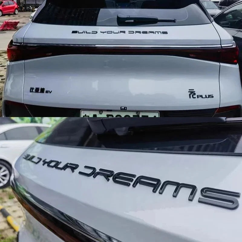 Black metallic BUILD YOUR DREAMS emblem installed on a white BYD EV rear trunk.