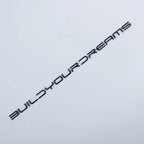 Black metallic decal sticker with the text BUILDYOURDREAMS in a modern font on a white background.