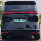 Rear view of a sleek black Denza D9 luxury MPV featuring a continuous red LED light bar.