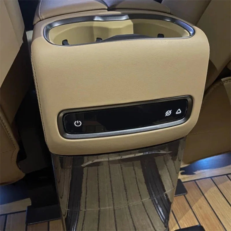 Tan leather car center console with dual cup holders and integrated black digital control panel.