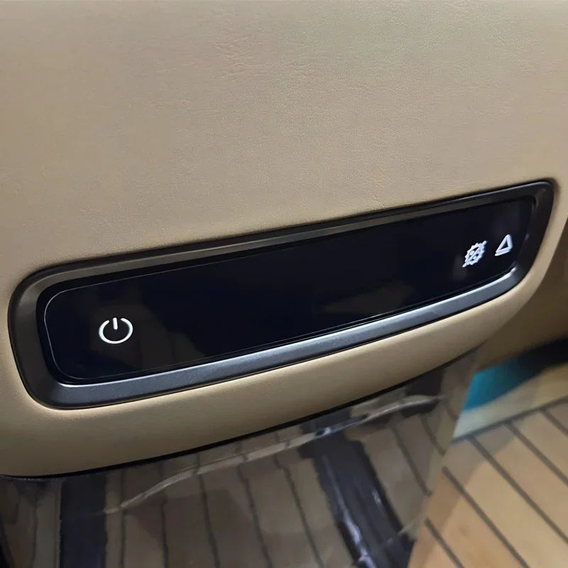 Black sleek control panel with power and hazard icons on tan leather car interior trim.