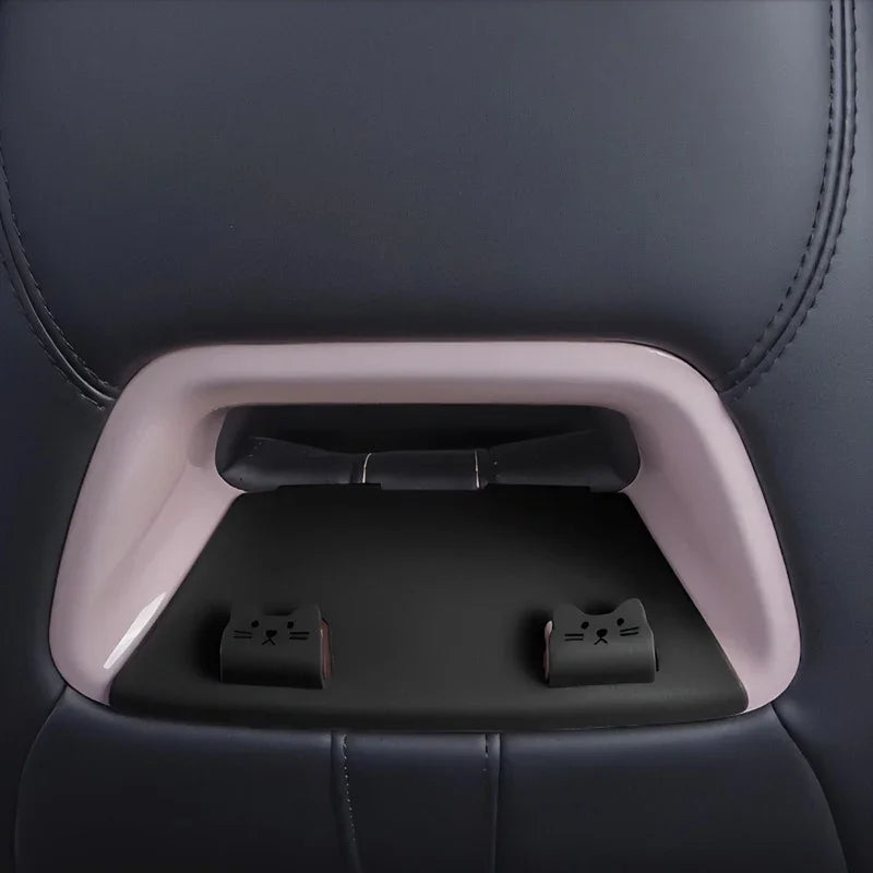 Cute cat-themed black seatbelt buckle covers on a grey car seat interior.