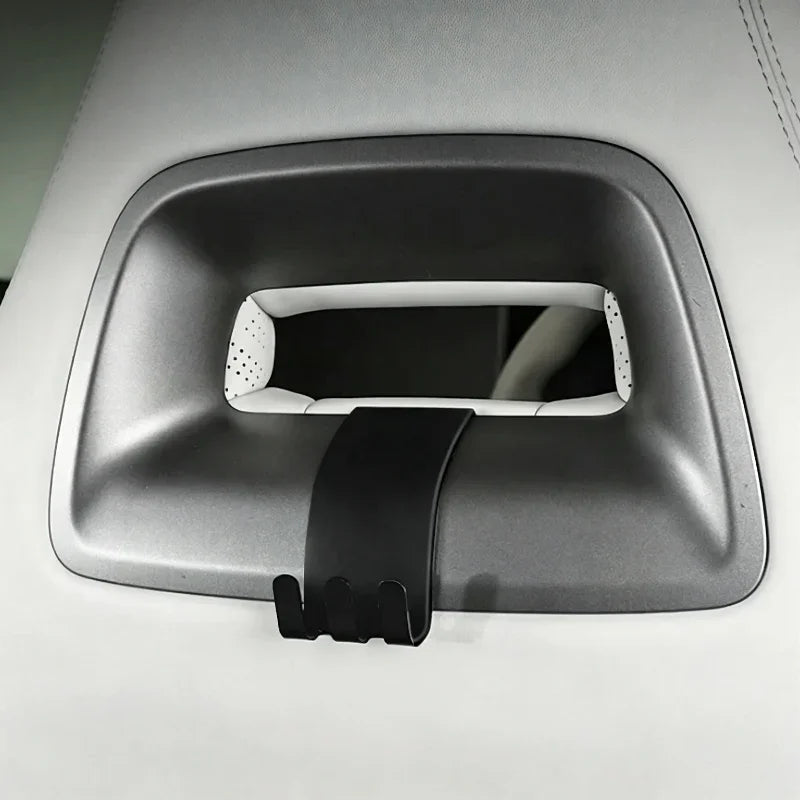 Black matte plastic grab handle hook accessory installed on a light grey car interior trim.
