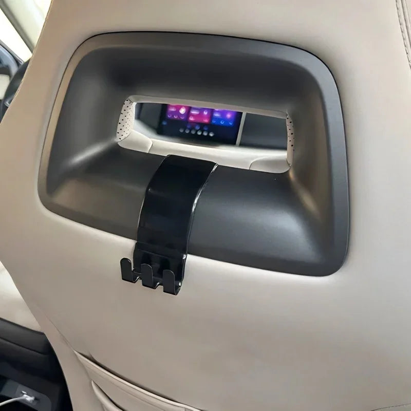 Black durable plastic car seat back hook installed on a beige leather car interior.