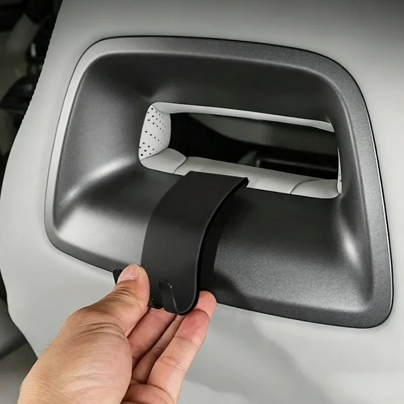 Hand installing a matte black plastic interior door handle cover for a BYD vehicle.