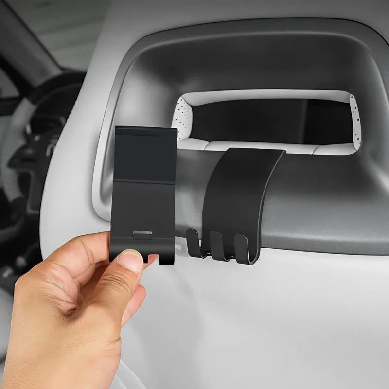 Hand installing a black matte plastic car seat back hook accessory.