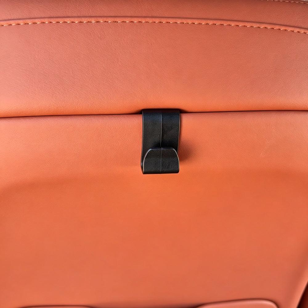 Black durable plastic seat clip on premium tan leather car upholstery.