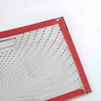 Red-trimmed perforated stainless steel tray with a sleek metallic finish.