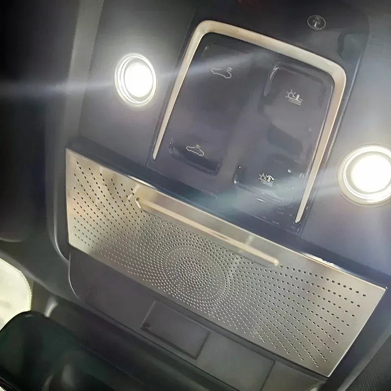 Silver perforated metal trim panel for car interior ceiling with integrated LED lights.