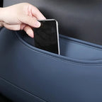 A hand sliding a smartphone into a navy blue faux leather car seat back pocket organizer.